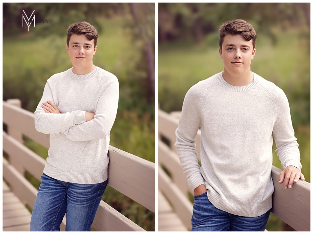 High school senior boy leaning against a bridge in a white sweater during his senior photo shoot.
