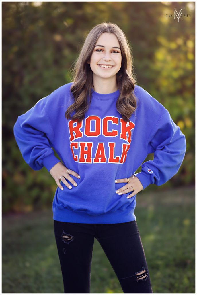 Senior girl wearing a University of Kansas sweatshirt at the senior photo shoot with Yvonne Min.