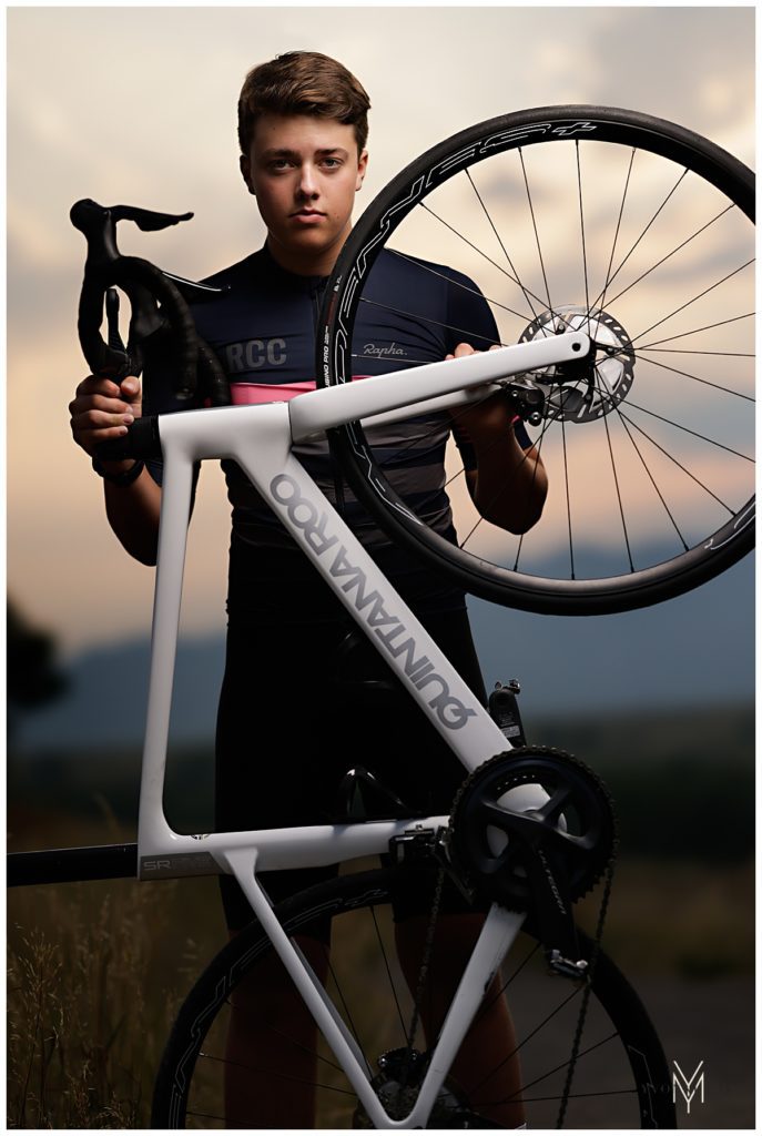 High school senior boy standing with his mountain racing bike in his biking gear with his mountain bike.