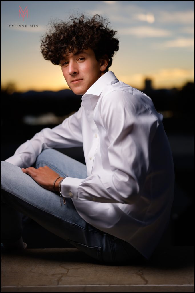 Owen poses of a senior photo using OCF at the stairs over looking downtown Denver at the Museum of Nature and Science.