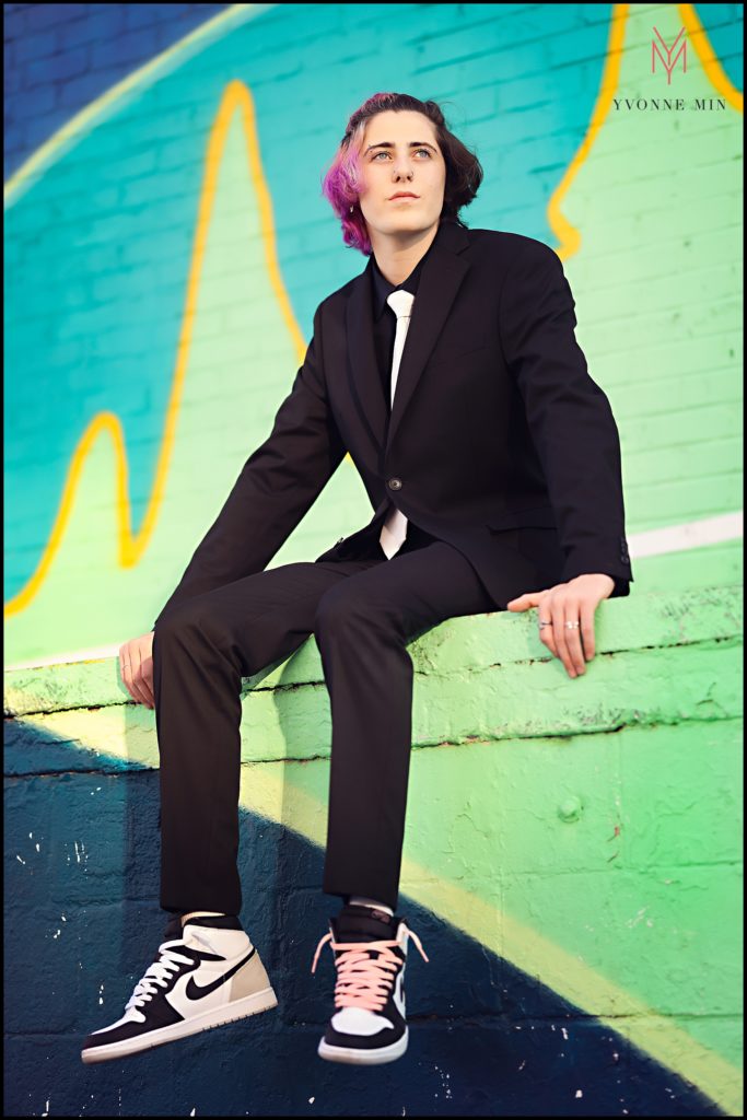 Mason sits on a colorfully painted ledge during his high school senior photoshoot in Rino, Denver.