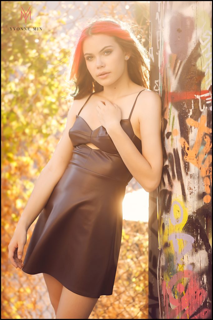 Leah leans on a light post covered in graffiti during her senior photo shoot in RiNo, Denver.
