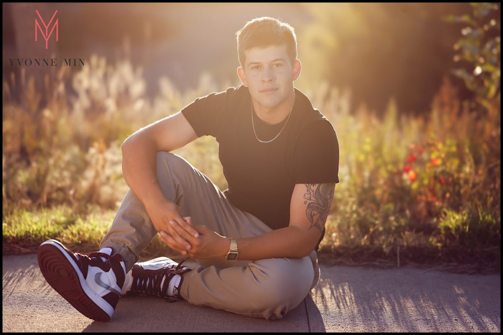 Greyson takes one of his high school senior photo images in the AIDS Memorial Park in LoDo, Denver.