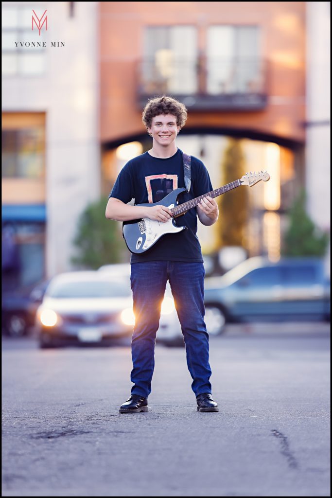 Cayden plays his guitar on a street in RiNo for one of his senior portraits.