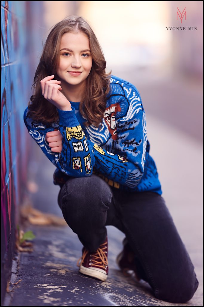 Claire kneels down in an alley in RiNo to pose for her high school senior photos.