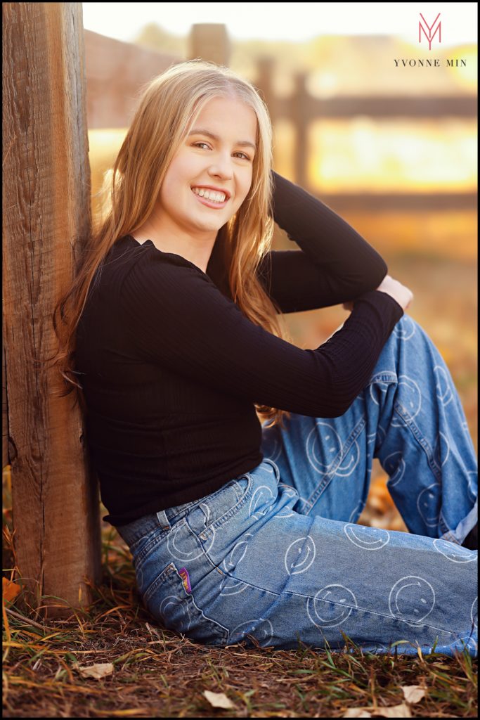Sydney leans against a fence in the parking lot of McKay Lake in Westminster, Colorado during her senior photoshoot.