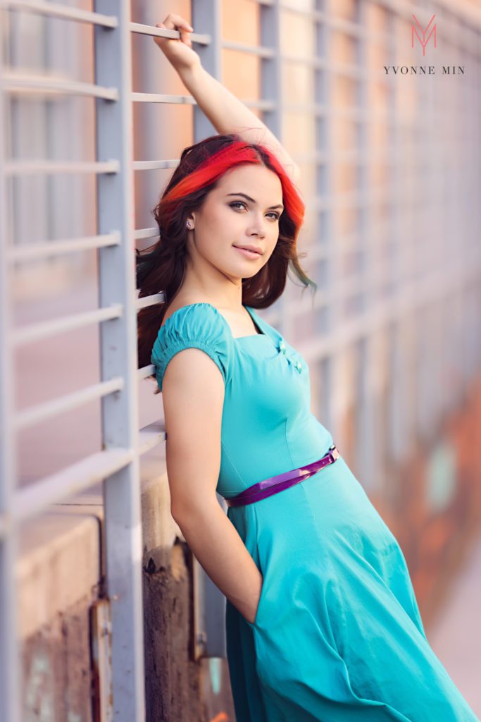 Wearing a teal colored dress, a senior high school girl poses during her photoshoot with Yvonne Min Photography.