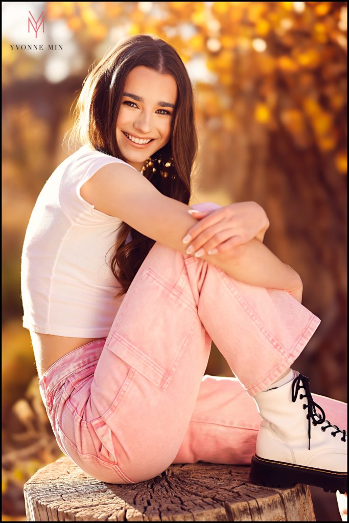 Izzy sits on a large tree stump for a senior photo taken at McKay Lake in Westminster, Colorado.