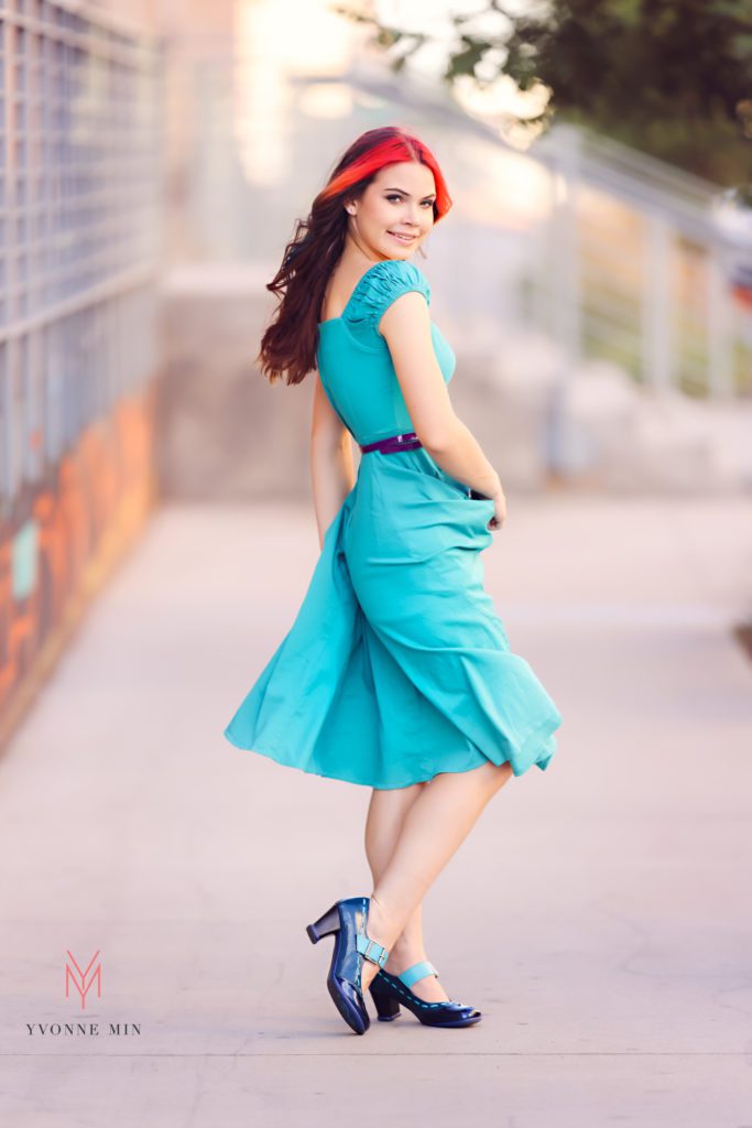 Wearing a teal colored dress and shoes, Leah poses for her senior photos in Denver with Yvonne Min Photography.
