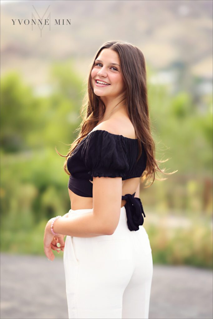 A high school senior girl smiles during her senior photoshoot in Golden, Colorado. 