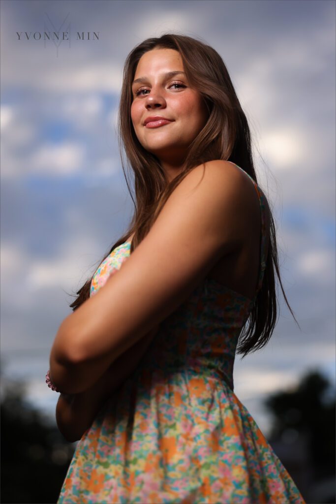 A senior girl poses in a floral dress at her senior photoshoot in Golden, Colorado with Yvonne Min Photography.
