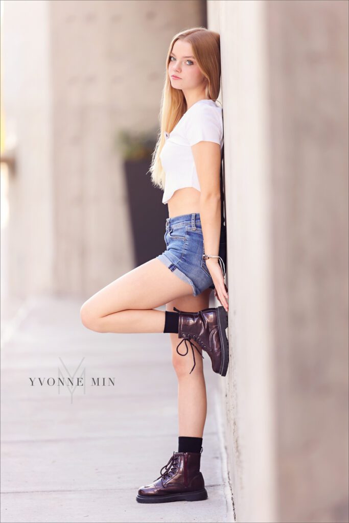 A high school senior cheerleader from Mountain Range High School poses against a wall during her senior photoshoot with Yvonne Min Photography in the RiNo District of Downtown Denver.
