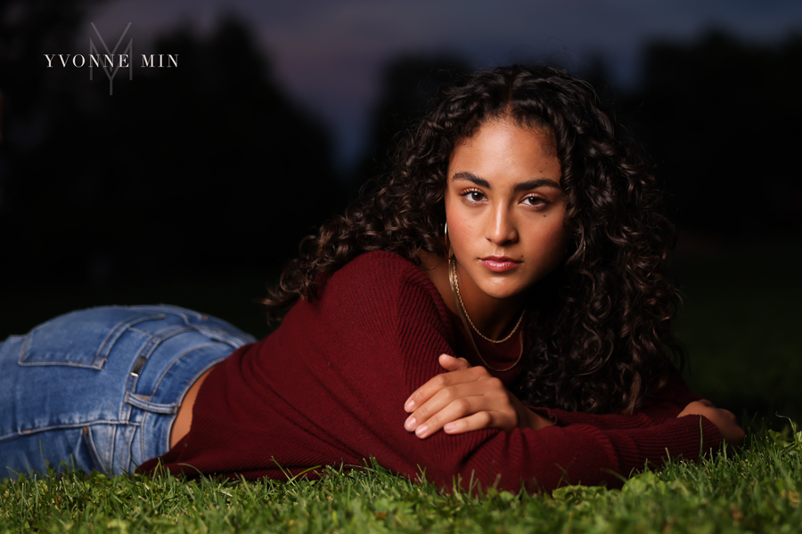 An off camera flash photo of a high school senior girl laying on the ground in Chautauqua Park in Boulder, Colorado taken by Yvonne Min Photography.