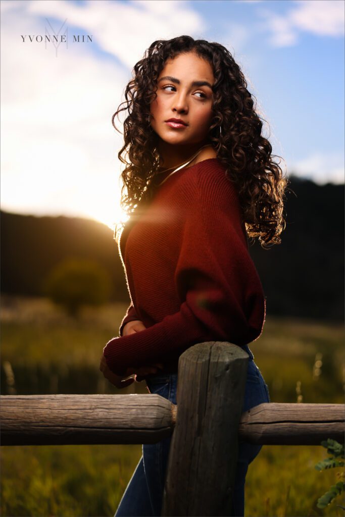 An off camera flash photo of a high school senior girl leaning on a fence rail in Chautauqua Park in Boulder, Colorado taken by Yvonne Min Photography.