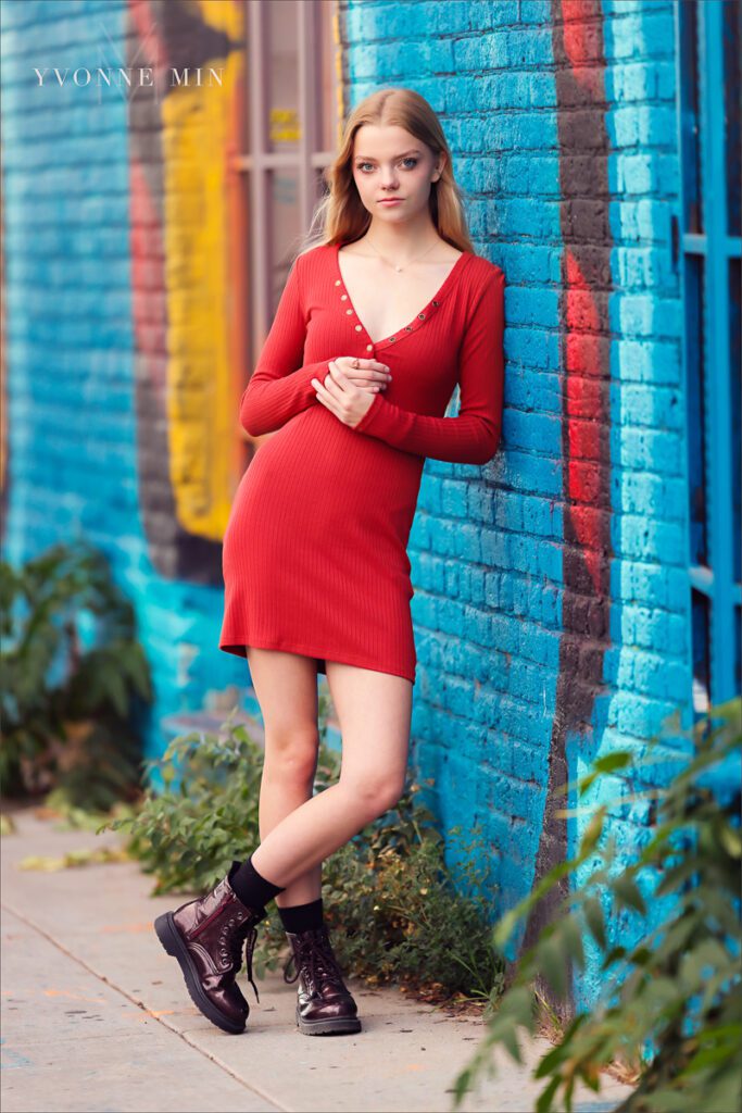 A high school senior from Mountain Range poses in a red dress at her senior photoshoot in the RiNo district of downtown Denver with Yvonne Min Photography.
