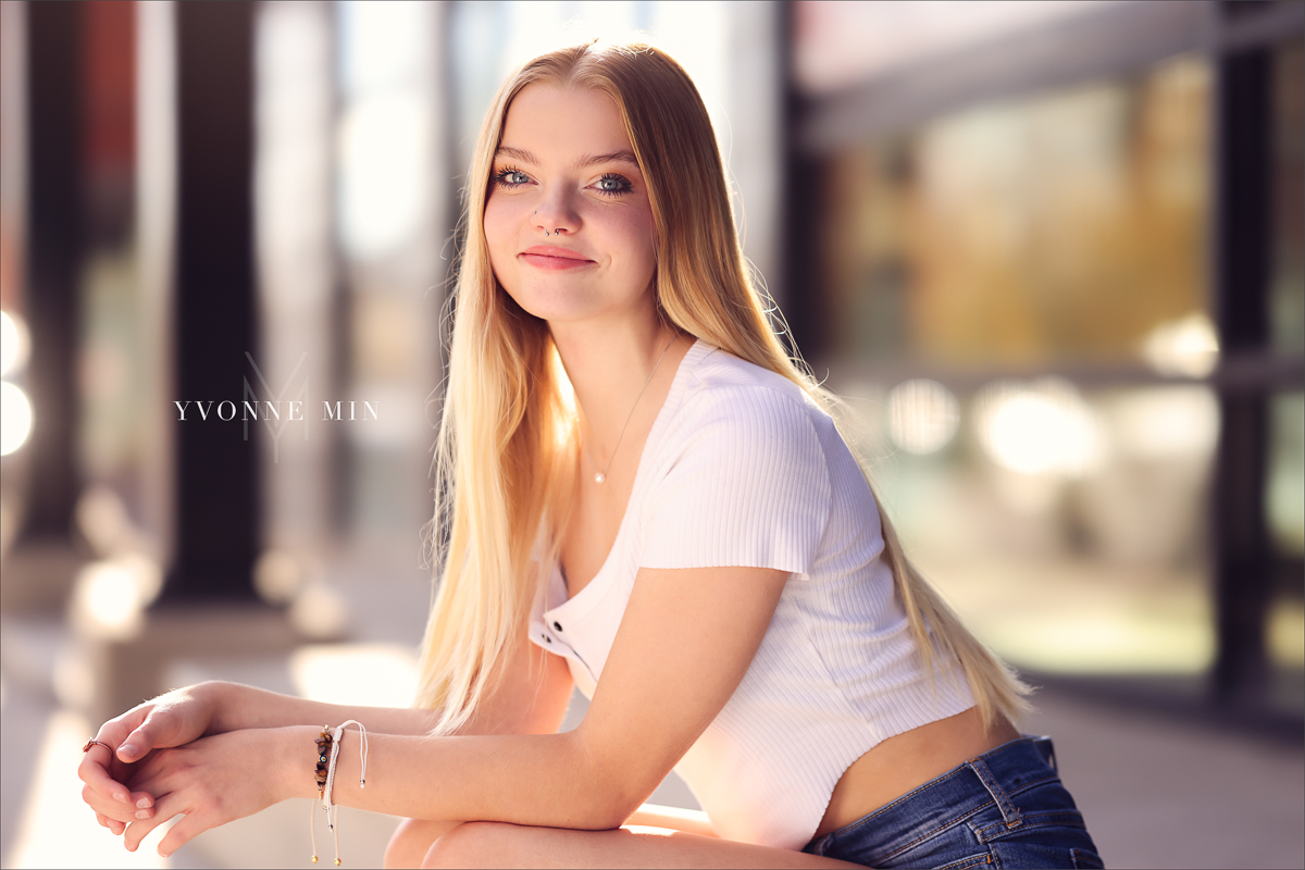 A high school senior cheerleader from Mountain Range High School poses on a railing during her senior photoshoot with Yvonne Min Photography in the RiNo District of Downtown Denver.