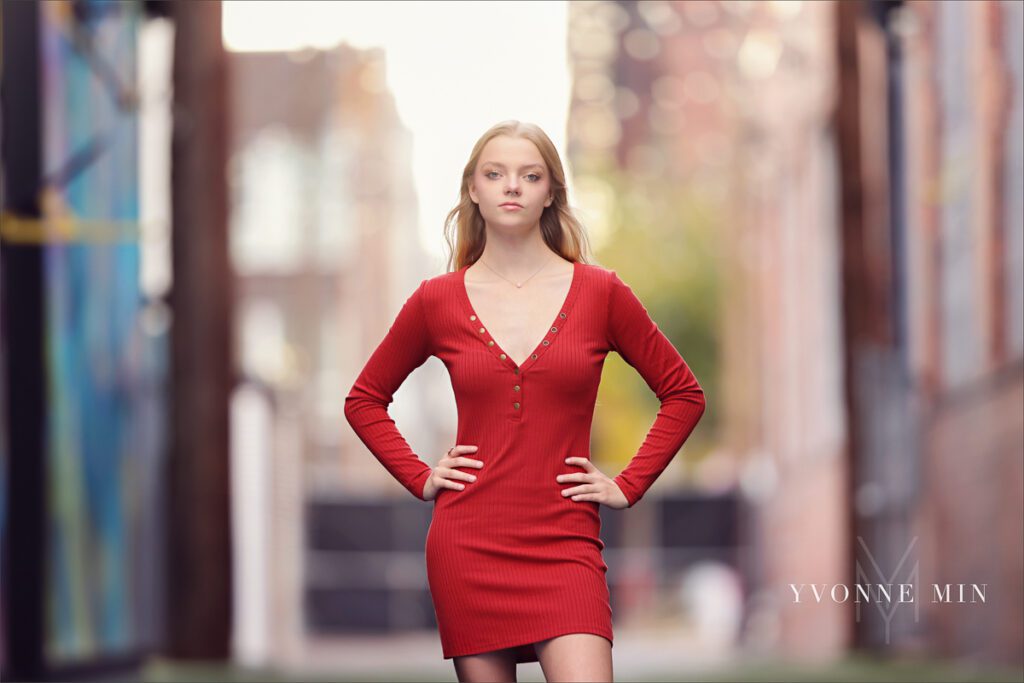 A high school senior from Mountain Range poses in a red dress at her senior photoshoot in the RiNo district of downtown Denver with Yvonne Min Photography.