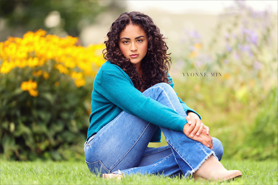 A senior girl poses in the grass in Chautauqua Park in Boulder Colorado during her senior photoshoot with Yvonne Min Photography.