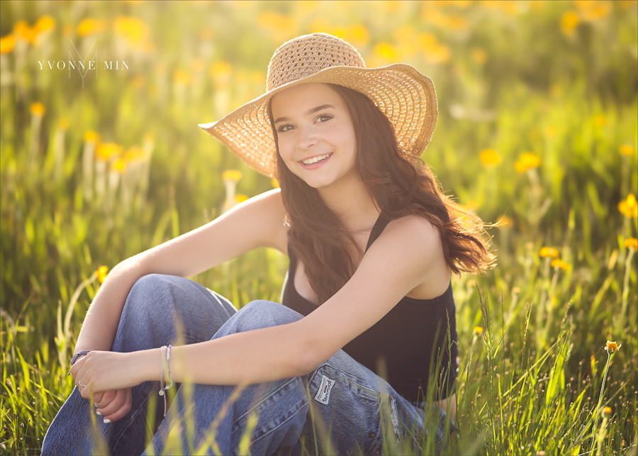 A Stargate High School senior girl sits in a field with yellow flowers at Flaitrons Vista outside Boulder, Colorado during her senior photoshoot with Yvonne Min Photography.