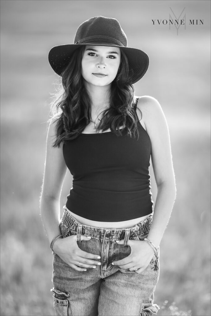 A black and white senior picture of a Stargate High School girl posing in a hat at her senior photoshoot at Flatirons Vista outside Boulder, Colorado with Yvonne Min Photography.