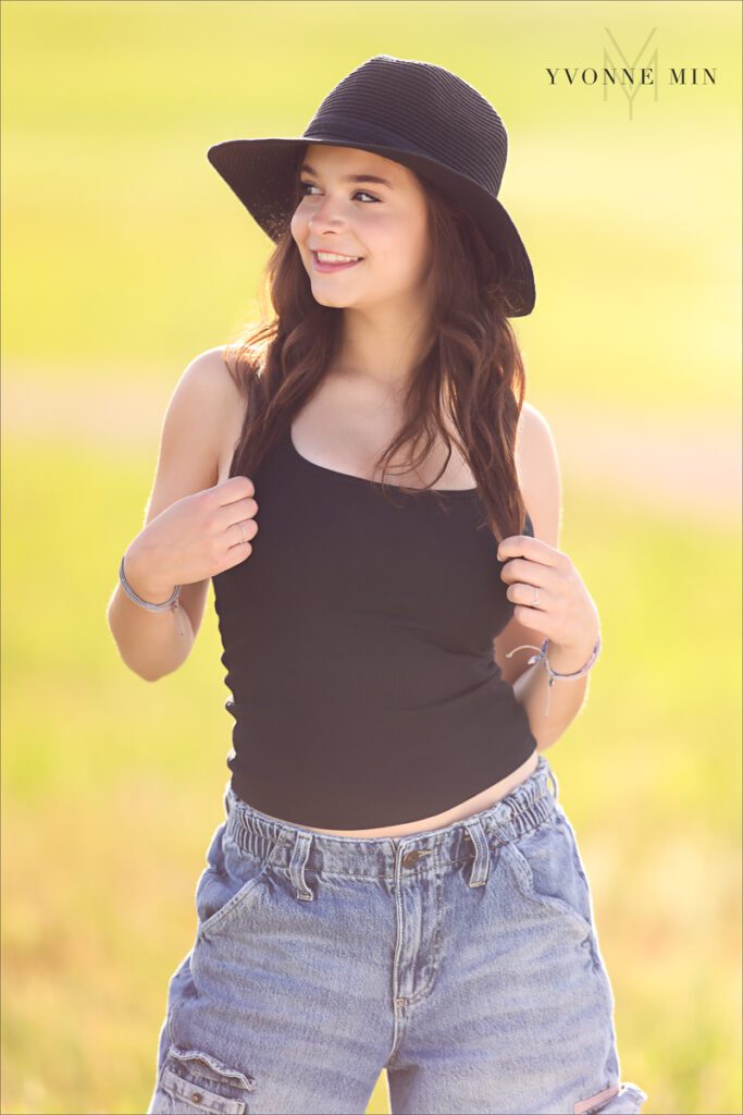 A Stargate High School senior girl poses in a black hat at Flaitrons Vista outside Boulder, Colorado during her senior photoshoot with Yvonne Min Photography.