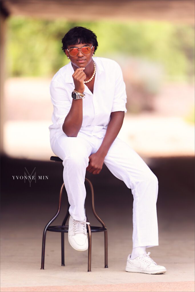 A high school senior picture of a Stargate student sitting on a stool at his senior photoshoot at Purple Park in Arvada with Yvonne Min Photography.