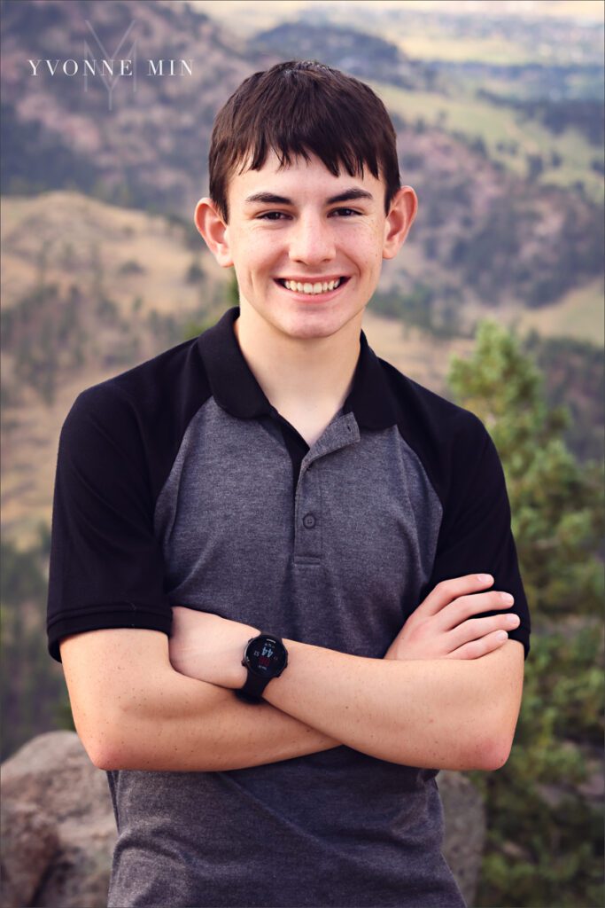 A senior picture of a Stargate High School senior boy in a gray t-shirt taken in the mountains above Boulder, Colorado by Yvonne Min Photography.