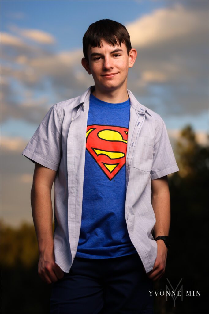 A senior photo of a Stargate High School boy in a superman t-shirt with a sunset in the mountains taken by Yvonne Min Photography in Boulder, Colorado.