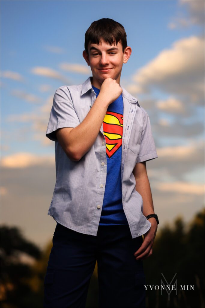 A senior photo of a Stargate High School boy in a superman t-shirt with a sunset in the mountains taken by Yvonne Min Photography in Boulder, Colorado.