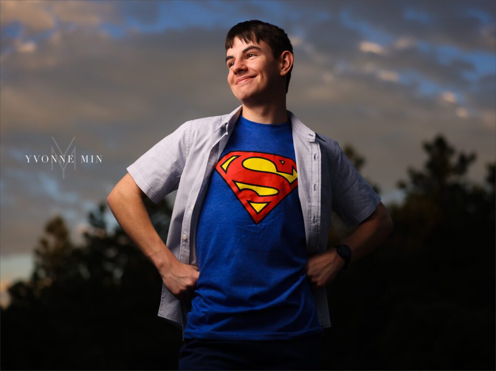 A senior photo of a Stargate High School boy in a superman t-shirt with a sunset in the mountains taken by Yvonne Min Photography in Boulder, Colorado.