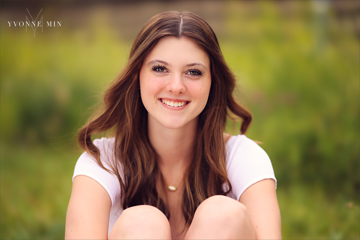 A Stargate High School senior girl poses for her senior pictures photoshoot in the grassy area of Purple Park, Superior, Colorado taken by Yvonne Min Photography.