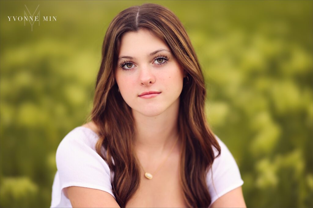 A Stargate High School senior girl poses for her senior pictures photoshoot in the grassy area of Purple Park, Superior, Colorado taken by Yvonne Min Photography.