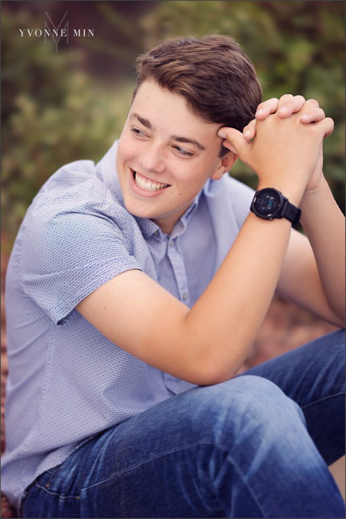 A senior picture of a Stargate High School boy sitting on a curb in Purple Park, Superior, Colorado by Yvonne Min Photography.