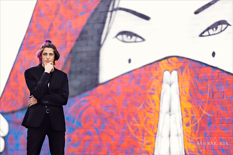 A high school senior poses in front of a mural in the art district of RiNo, Denver with Yvonne Min Photography.