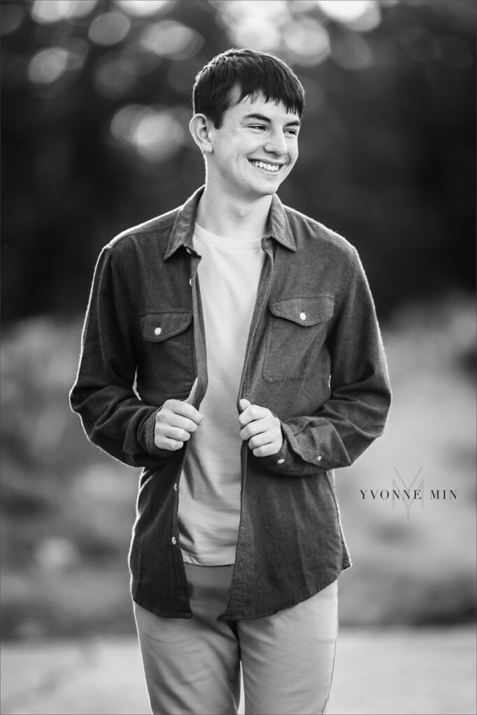 A black and white senior picture of a Stargate High School boy walking on a trail at Artist's Point above Boulder, Colorado taken by Yvonne Min Photography.