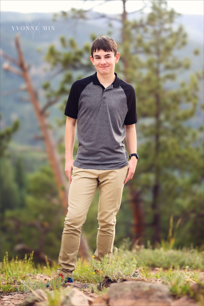 A senior picture of a Stargate High School senior boy in a gray t-shirt taken in the mountains above Boulder, Colorado by Yvonne Min Photography.