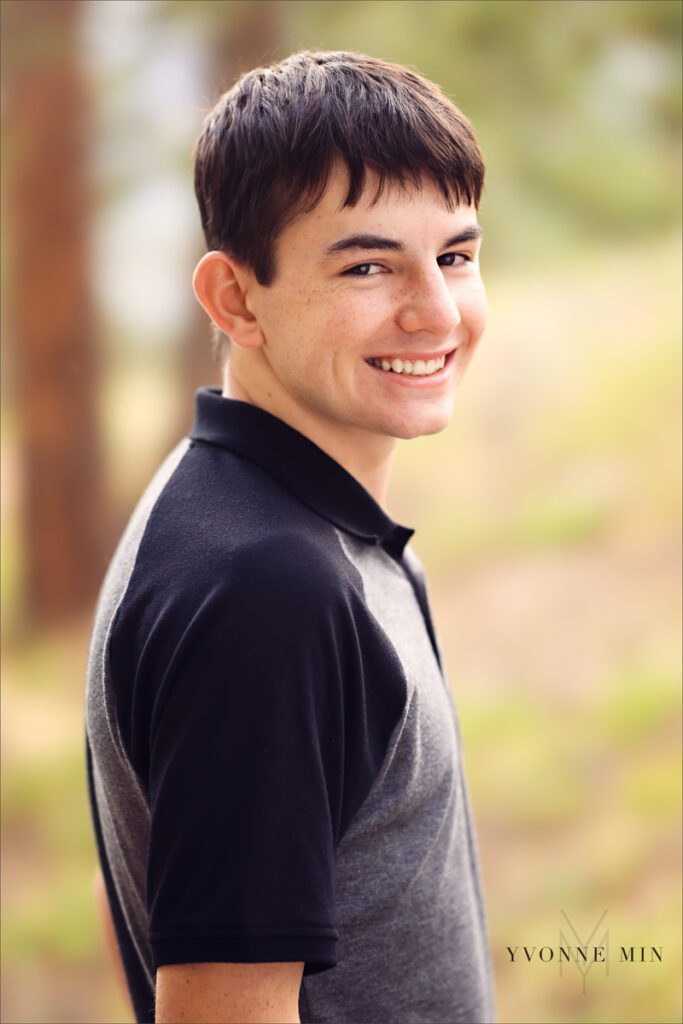 A senior picture of a Stargate High School senior boy in a gray t-shirt taken in the mountains above Boulder, Colorado by Yvonne Min Photography.