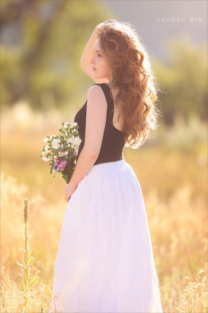 A high school senior girl from Stargate poses with a bouquet of flowers at her senior photoshoot with Yvonne Min Photography at South Mesa Trailhead.