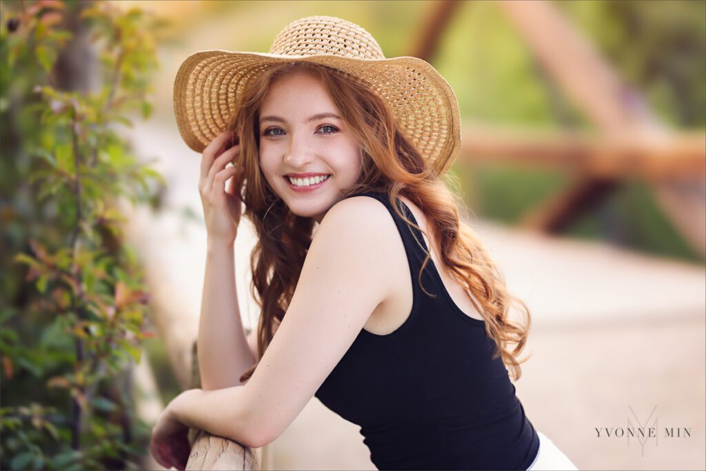 High school senior picture of a Stargate student wearing g hat and leaning on a fence taken by Yvonne Min Photography at South Mesa Trailhead.
