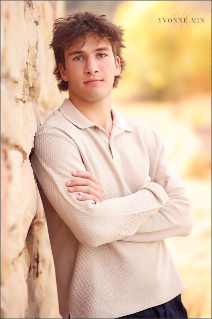 A senior boy leans against the historical out building at his senior photoshoot at South Mesa in Boulder with Yvonne Min Photography.