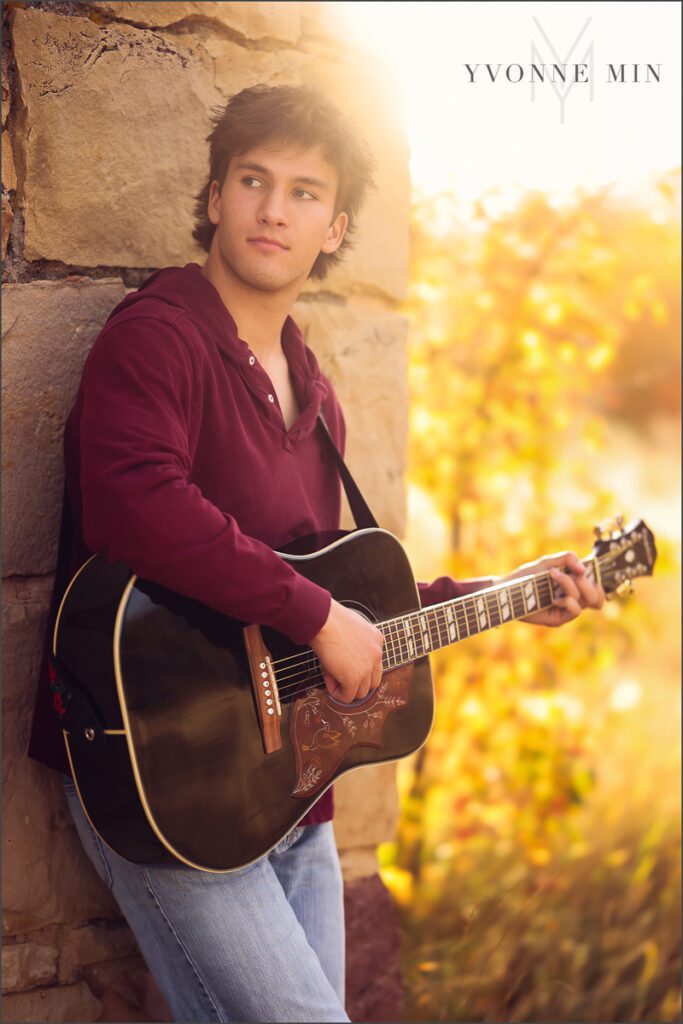 A senior guy from Nothfield High Schools plays a guitar during his senior photoshoot at South Mesa Trailhead outside Boulder with Yvonne Min Photography.