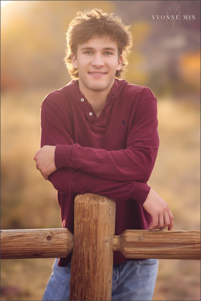 A senior boy poses on a fence at his senior photoshoot at South Mesa in Boulder with Yvonne Min Photography.