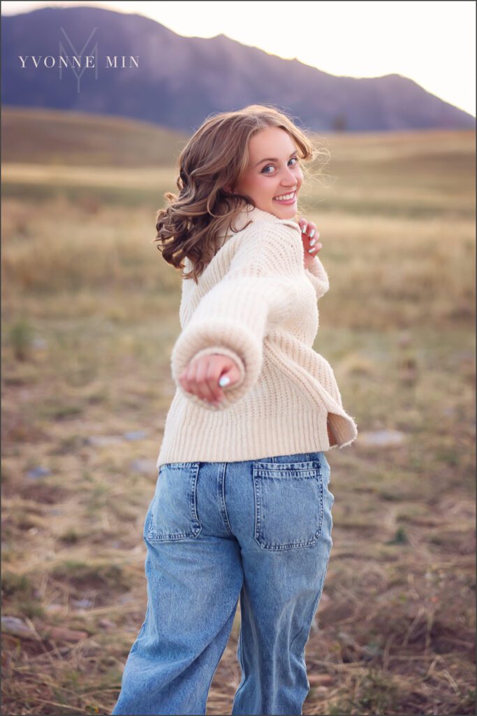 A high school senior girl from Jefferson Academy laughs at her senior photoshoot with Yvonne Min Photography at Flatirons Vista outside Boulder.