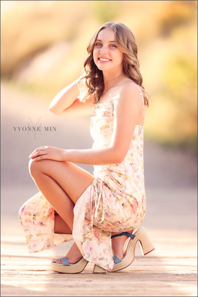 A high school senior girl from Jefferson Academy poses on a bridge at her senior photoshoot at South Mesa Trailhead outside Boulder with Yvonne Min Photography.
