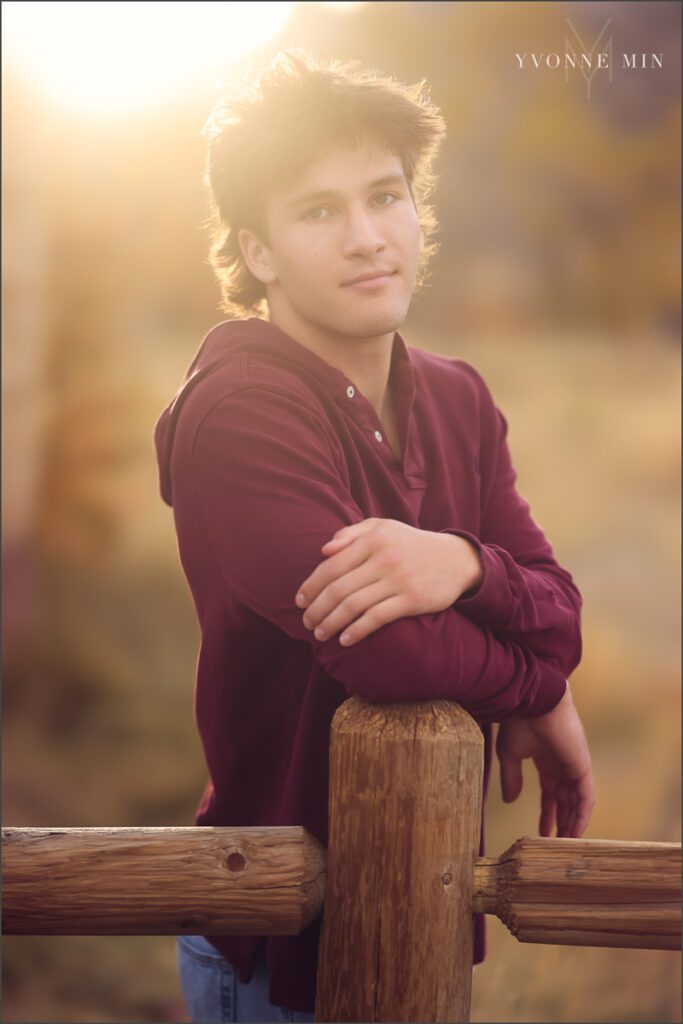 A senior boy poses on a fence at his senior photoshoot at South Mesa in Boulder with Yvonne Min Photography.