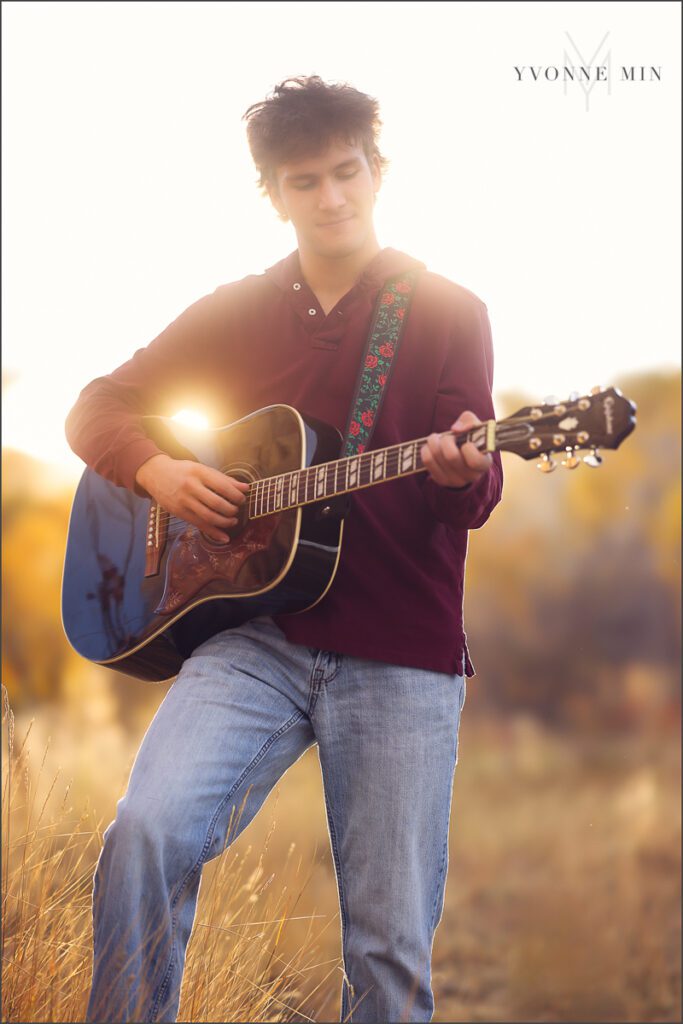 A senior guy from Nothfield High Schools plays a guitar during his senior photoshoot at South Mesa Trailhead outside Boulder with Yvonne Min Photography.