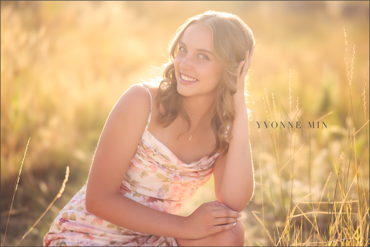 A high school senior girl poses in a field at her senior photoshoot at South Mesa Trailhead outside Boulder with Yvonne Min Photography.