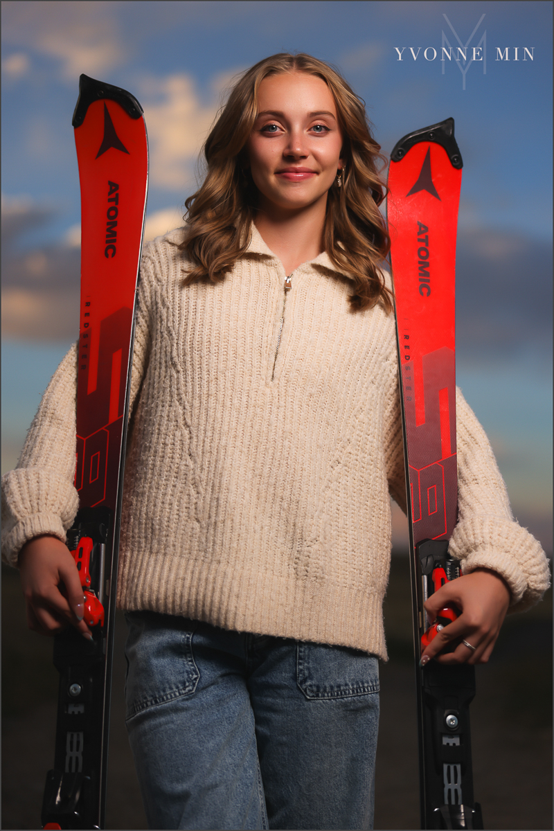 An OCF (off camera flash)senior photo of a girl holding skis from Jefferson Academy at her senior photoshoot with Yvonne Min Photography at Flatirons Vista Trailhead outside Boulder, Colorado.