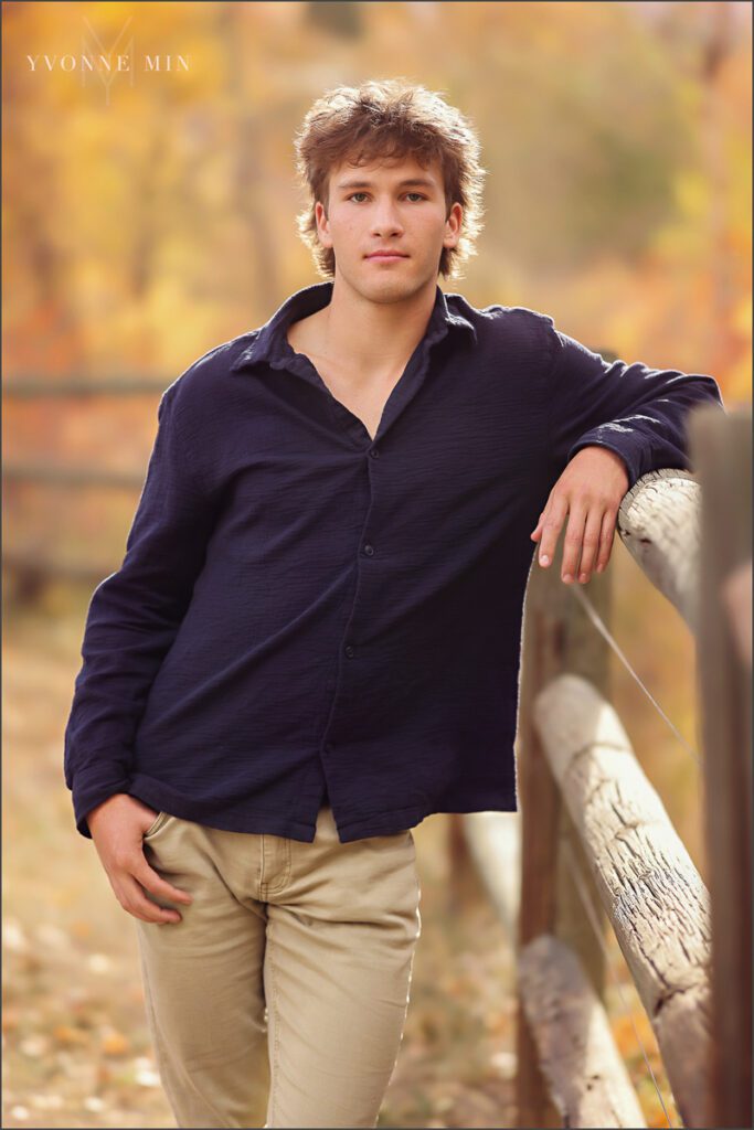 A senior boy poses on a fence at his senior photoshoot at South Mesa in Boulder with Yvonne Min Photography.