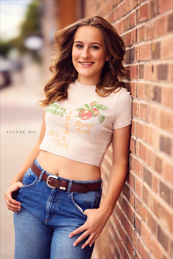 A high school senior picture of a student from Legacy High School posing against a wall in downtown Louisville, Colorado with Yvonne Min Photography.